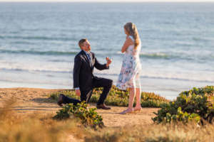 Beach proposal with ocean backdrop.